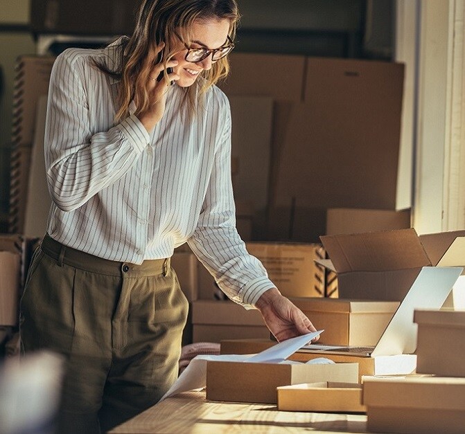 a woman looking at an invoice surrounded by boxes